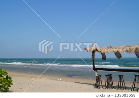 A beautiful place to relax and unwind on the beach by the sea. A beautiful bamboo and straw bar counter sits against a backdrop of blue sky and turquoise sea.A cozy place to relax on the beach. A beautiful place to relax and unwind on the beach by the sea. A beautiful bamboo and straw bar counter sits against a backdrop of blue sky and turquoise sea.A cozy place to relax on the beach. 135003059