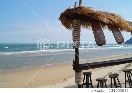 A beautiful place to relax and unwind on the beach by the sea. A beautiful bamboo and straw bar counter sits against a backdrop of blue sky.A cozy place to relax on the beach. 135003085
