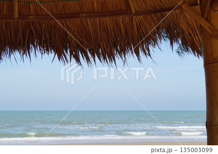 A cozy place to relax on the beach.A beautiful place for relaxation and recreation on the beach by the sea. A bamboo and thatch roof set against a backdrop of blue sky and turquoise sea. A cozy place to relax on the beach.A beautiful place for relaxation and recreation on the beach by the sea. A bamboo and thatch roof set against a backdrop of blue sky and turquoise sea. 135003099