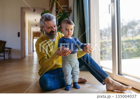 Father with little toddler son looking out of window. 135004037