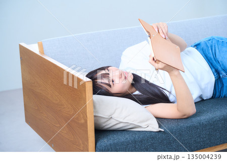 ソファで手帳を見る若い日本人女性 ソファで手帳を見る若い日本人女性 135004239