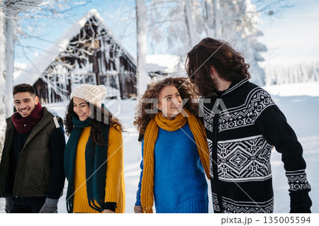 Friends walking through winter forest in snowy landscape. 135005594