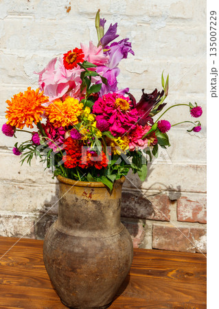 Bouquet of flowers in antique rustic clay jug against white brick wall Bouquet of flowers in antique rustic clay jug against white brick wall 135007229