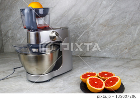 Modern electric juicer and grapefruits on a kitchen table. Preparing fresh squeezed grapefruit juice 135007286