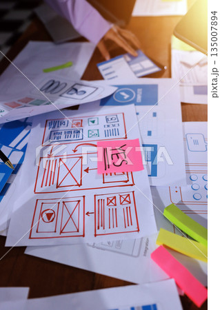 Close up ux developer and ui designer brainstorming about mobile app interface wireframe design on table with customer breif and color code at modern office.Creative digital development agency. Close up ux developer and ui designer brainstorming about mobile app interface wireframe design on table with customer breif and color code at modern office.Creative digital development agency. 135007894