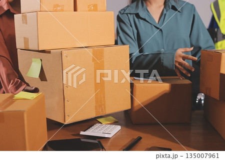 Startup SME small business entrepreneur of freelance Asian woman wearing apron using laptop and box to receive and review orders online to prepare to pack sell to customers, online sme business ideas. 135007961