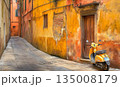 Yellow Vespa parked on a narrow street with aged, textured build 135008179