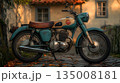 Weathered Teal Motorcycle Parked on Cobblestone with Autumn Leav 135008181