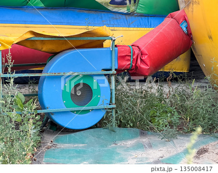 Inflatable blower beside a deflated bounce house. Inflatable blower beside a deflated bounce house. 135008417