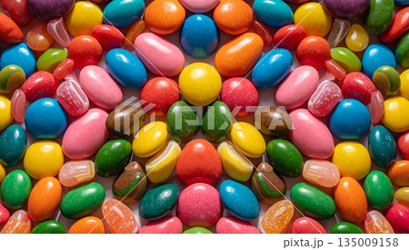 A vibrant group of colorful chocolate candies and jelly beans creates a bright confectionery texture of sweet round snacks including green and orange sugar dragee A vibrant group of colorful chocolate candies and jelly beans creates a bright confectionery texture of sweet round snacks including green and orange sugar dragee 135009158