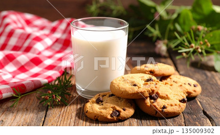 A delicious stack of homemade chocolate chip cookies sits next to a fresh glass of white milk, creating a sweet baked snack and healthy breakfast beverage isolated on a brown background A delicious stack of homemade chocolate chip cookies sits next to a fresh glass of white milk, creating a sweet baked snack and healthy breakfast beverage isolated on a brown background 135009302