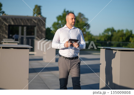Professional male standing outside using digital tablet Professional male standing outside using digital tablet 135009808