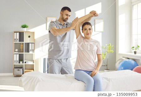 Chiropractor or physical therapist working with young woman's arm in rehabilitation hospital. Chiropractor or physical therapist working with young woman's arm in rehabilitation hospital. 135009953