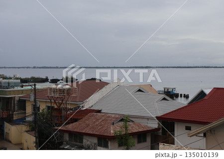 曇り空と対岸の陸と海と家のある町並みの風景 曇り空と対岸の陸と海と家のある町並みの風景 135010139