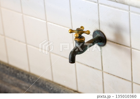 closeup of old style brass water tap installed in public rest room.  135010360