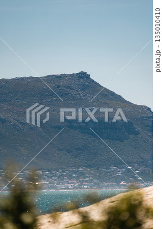 Scenic view of a mountain overlooking a small coastal town next to the ocean Scenic view of a mountain overlooking a small coastal town next to the ocean 135010410
