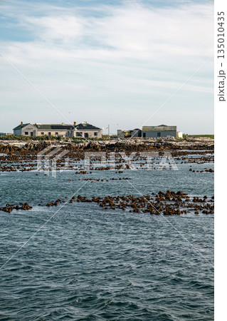Distant view of small settlement on rocky island from ocean. Coastal landscape 135010435