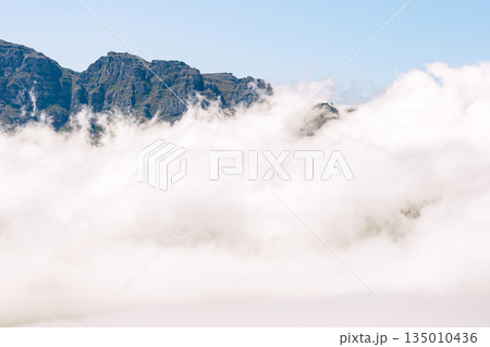 Foggy mountain landscape with clouds covering the lower part of the peak Foggy mountain landscape with clouds covering the lower part of the peak 135010436