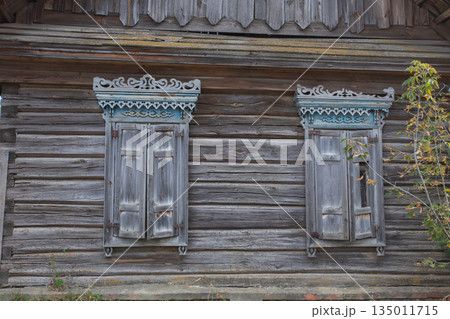 Two windows on a building with a wooden frame. The windows are open and the frame is old 135011715