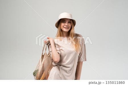 Young woman holding reusable mesh shopping bag with fresh vegetables and bread, minimal sustainable lifestyle, eco friendly shopping and healthy food choices Young woman holding reusable mesh shopping bag with fresh vegetables and bread, minimal sustainable lifestyle, eco friendly shopping and healthy food choices 135011860