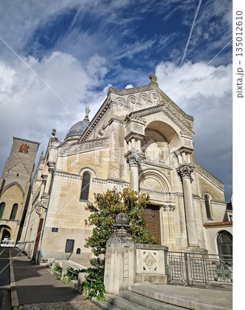 Basilica of Saint Martin in Tours, France. Neo-Byzantine church outdoor view of the grand arched entrance, and prominent dome topped with a statue. The medieval Charlemagne Tower stands near the abbey 135012610