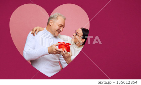 Lifestyle poster of mature couple with gift box inside heart. 135012854