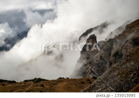 Fog rolling over rugged Dolomites mountains and rocky alpine slopes 135013095