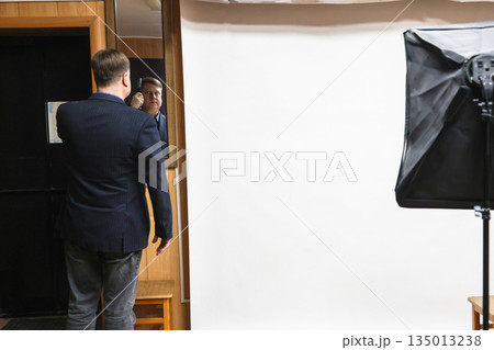 Man Combing Hair in Front of Mirror at Professional Photo Studio 135013238