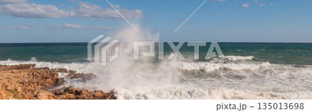 Powerful surf hitting rocks emerald blue sea white foam and clear sky. Powerful surf hitting rocks emerald blue sea white foam and clear sky. 135013698