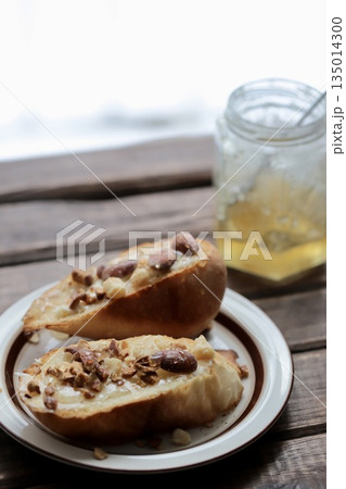 窓辺に置いたミックスナッツのハニーバタータルティーヌとハチミツの瓶 135014300