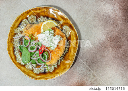 Breaded schnitzel with creamy sauce, lemon and fresh salad on rustic plate Breaded schnitzel with creamy sauce, lemon and fresh salad on rustic plate 135014716