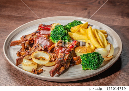 Grilled pork ribs with barbecue sauce french fries broccoli and roasted onions on plate Grilled pork ribs with barbecue sauce french fries broccoli and roasted onions on plate 135014719
