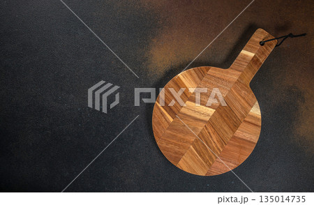 Round wooden cutting board on dark background, top view, copy space Round wooden cutting board on dark background, top view, copy space 135014735