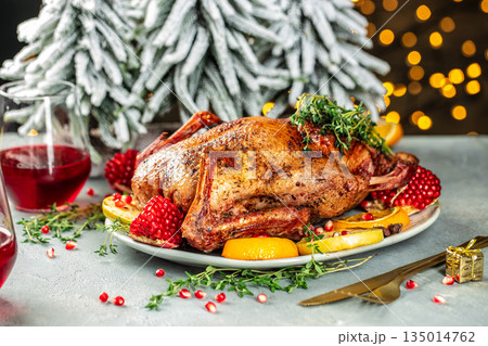 Festive roasted duck with oranges and pomegranate on a holiday table with Christmas decorations 135014762