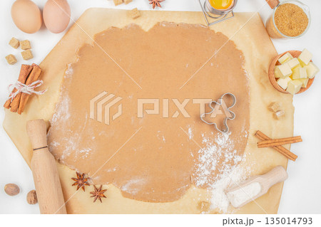 Gingerbread dough with cookie cutter, rolling pin, and baking ingredients on kitchen table, top view, free space for text Gingerbread dough with cookie cutter, rolling pin, and baking ingredients on kitchen table, top view, free space for text 135014793