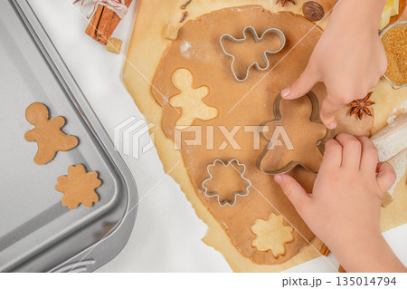 Children cutting gingerbread cookies from dough with cutters on kitchen table, top view, free space for text Children cutting gingerbread cookies from dough with cutters on kitchen table, top view, free space for text 135014794