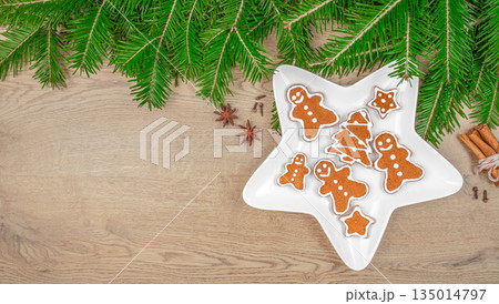 Gingerbread cookies with icing in star shaped plate and Christmas decorations on wooden background, top view, free space for text 135014797