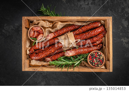 Smoked sausages with herbs and spices in a wooden box with copy space on dark background 135014853