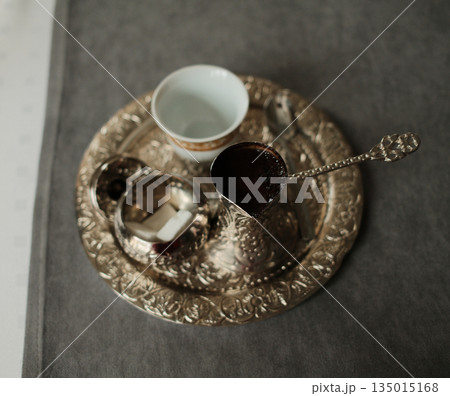 Top view of traditional Bosnian coffee with cezve, sugar cubes and cup on decorative tray. Concept of ritual, culture and authentic Balkan lifestyle Top view of traditional Bosnian coffee with cezve, sugar cubes and cup on decorative tray. Concept of ritual, culture and authentic Balkan lifestyle 135015168