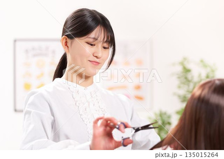 お客の髪をカットする若い女性美容師 135015264