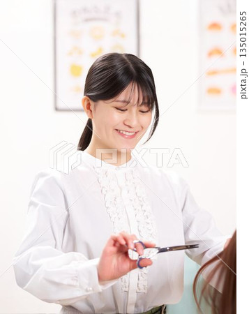 お客と会話しながら髪を切るヘアスタイリスト 135015265