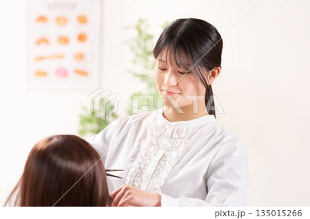 お客の髪をカットする若い女性美容師 135015266