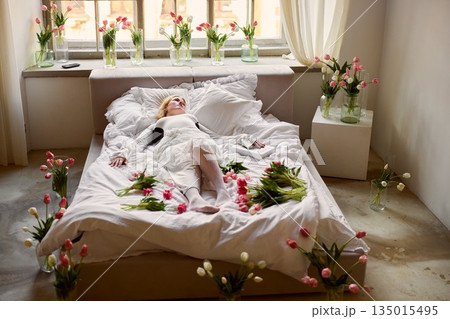 Serene bride in floral setting, Calm bride lying peacefully surrounded by vibrant tulip blossoms Serene bride in floral setting, Calm bride lying peacefully surrounded by vibrant tulip blossoms 135015495