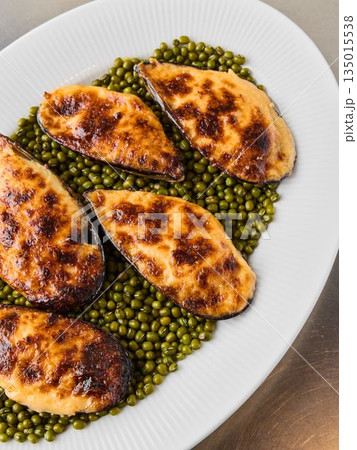 Elegant serving of roasted mussels on peas with lemon wedge 135015538