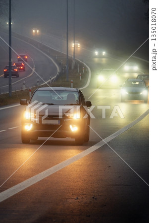 Bright headlights of a car driving on foggy winter road Bright headlights of a car driving on foggy winter road 135018070