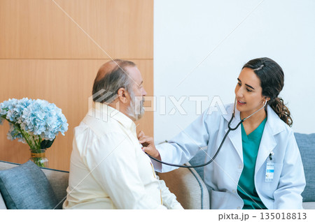 Young female doctor in white medical coat attending physician using stethoscope listening an old patient for checking heartbeat. Medicine and health care concept. cardiology concept. Young female doctor in white medical coat attending physician using stethoscope listening an old patient for checking heartbeat. Medicine and health care concept. cardiology concept. 135018813