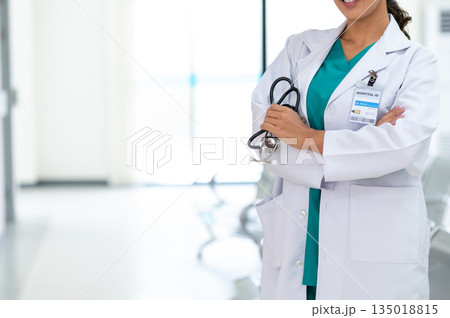 Medicine female doctor wearing a white medical gown with stethoscope in hand standing in hospital corridor. Health care and medical or Health Insurance concept. Medicine female doctor wearing a white medical gown with stethoscope in hand standing in hospital corridor. Health care and medical or Health Insurance concept. 135018815