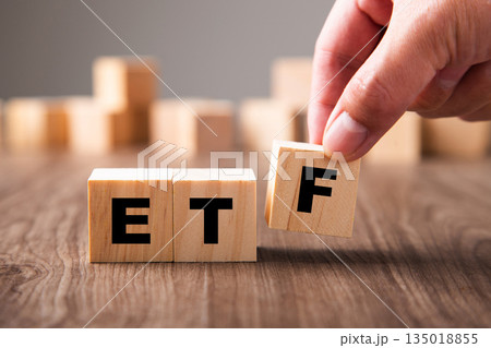 Hand placing wooden block creating etf acronym 135018855