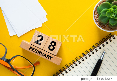February 28 date block calendar on yellow desk 135018871