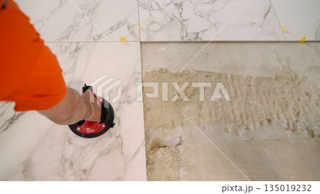 Construction worker placing marble tile using suction cup tool 135019232